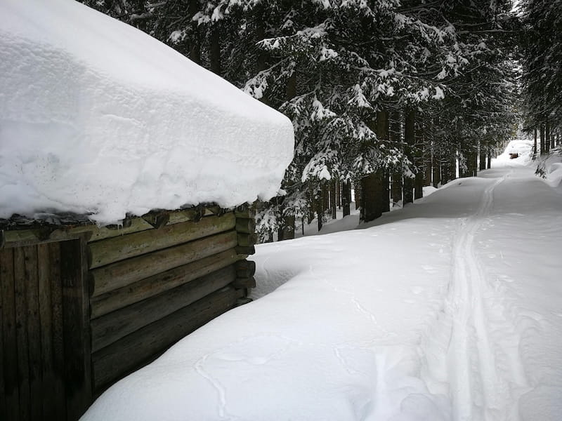 Estrada de neve com casa de madeira