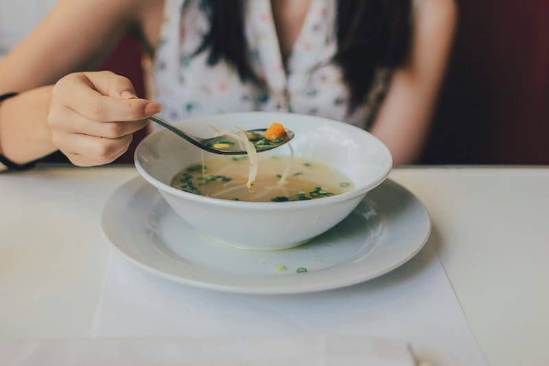 O que comer em viagens de neve no Chile: pratos, restaurantes e dicas práticas Mulher comendo sopa